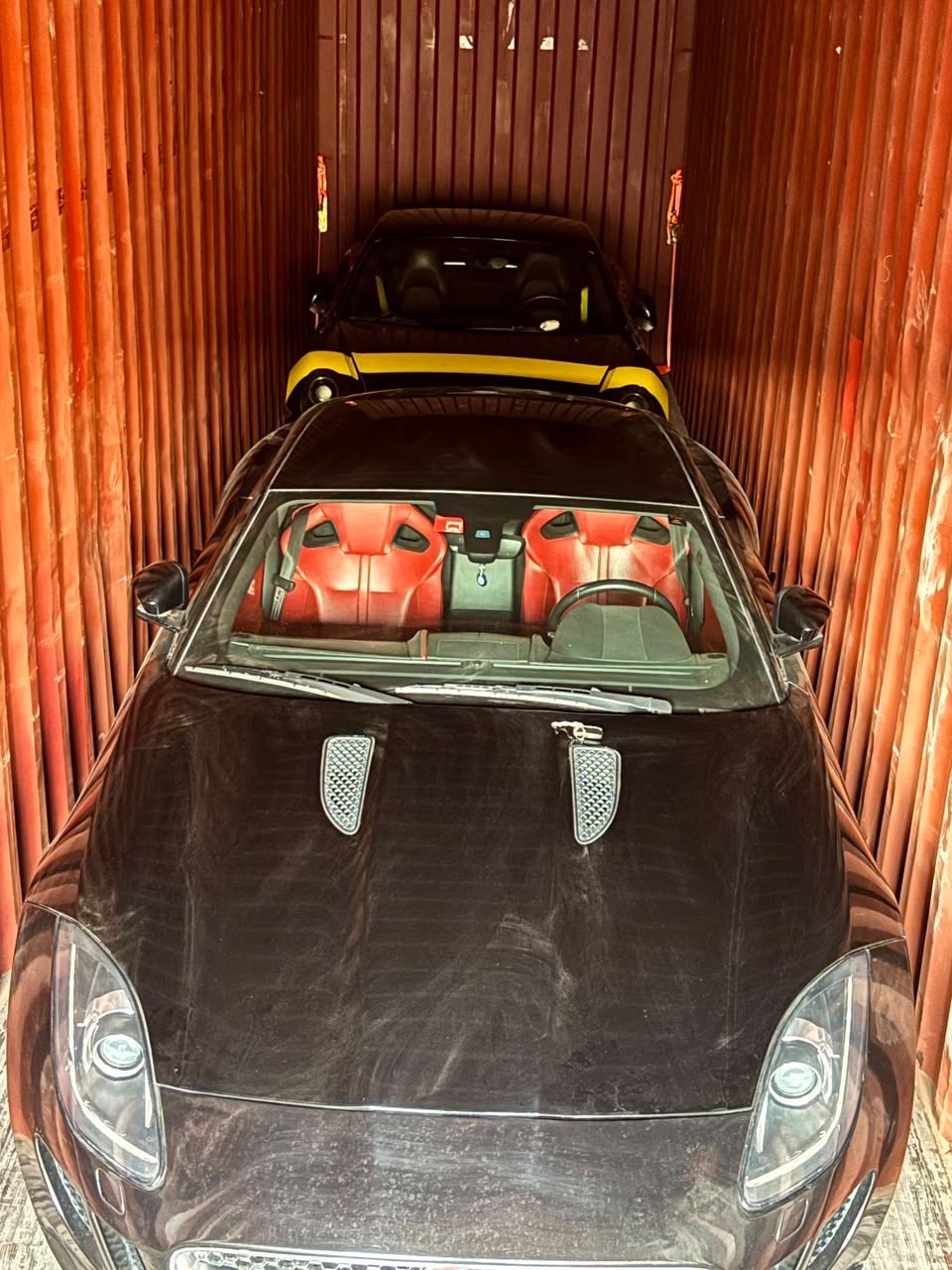Porsche, black with yellow accent line, in transit to Europe